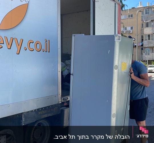אדם מעמיס מקרר למשאית הובלה ברחוב